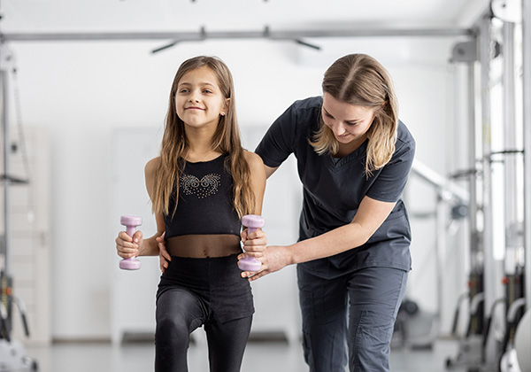 Rehabilitation specialist helping little girl with exercises
