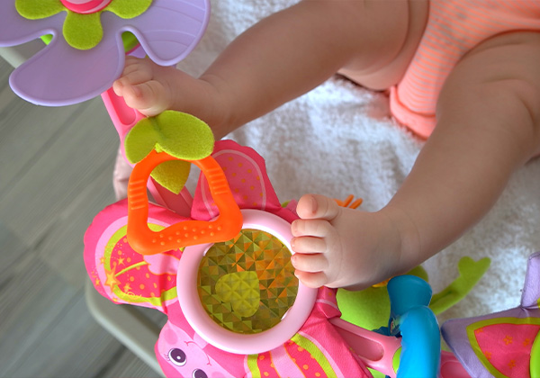 Newborn baby playing with toys in crib.